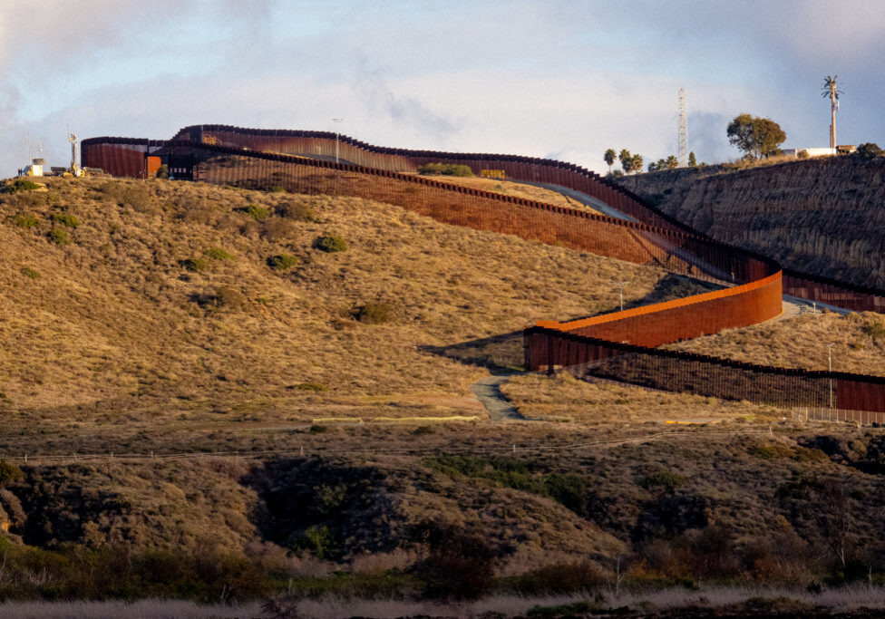 The US/Mexico border fence winds up and down the hills dividing the two countries.